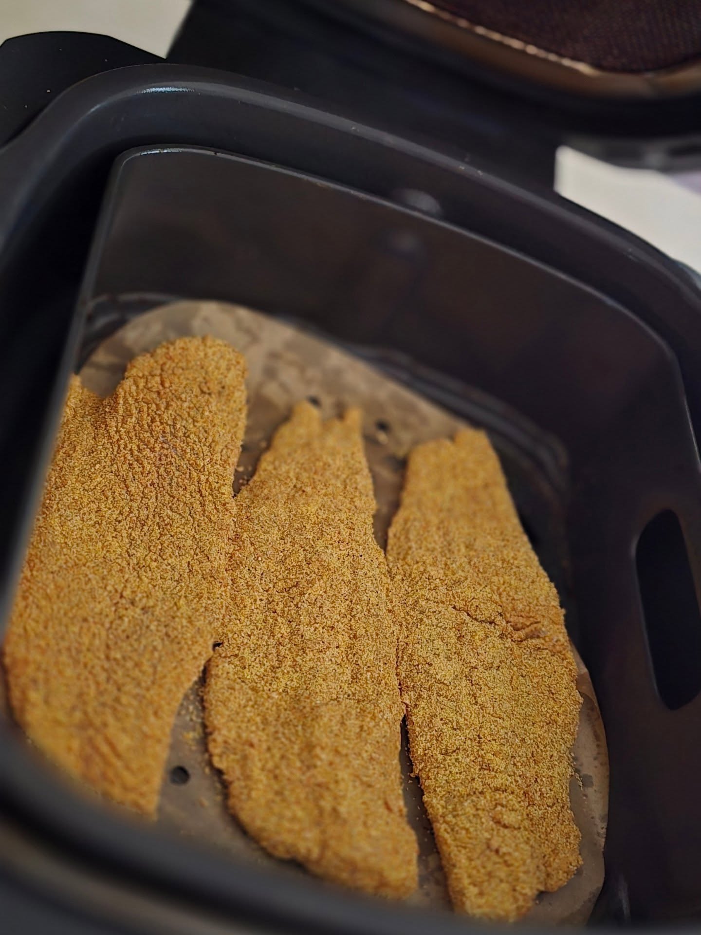 Golden crispy fried fish fillets coated in Frenzy Fish Fry mix cooking in an air fryer basket